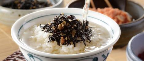 A bowl of rice topped with seaweed and sesame seeds, with a spoon lifting some of the rice.