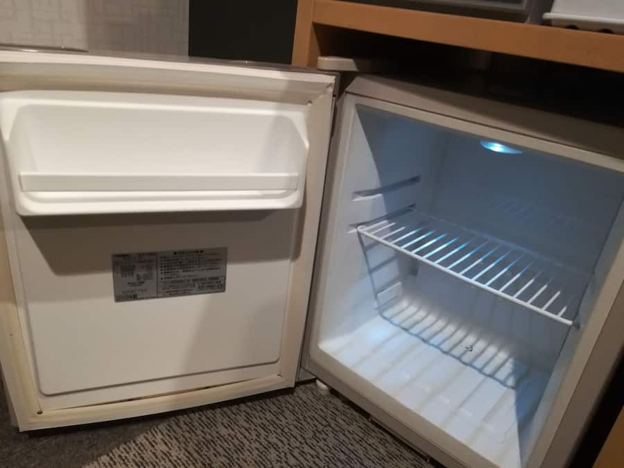 Ein offener Kühlschrank mit einem Aufkleber an der Tür und einem Einleger im Inneren.