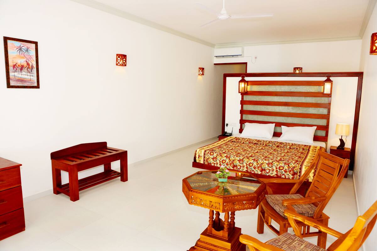 Una habitación de hotel con una cama, un banco de madera, una mesita y una silla.