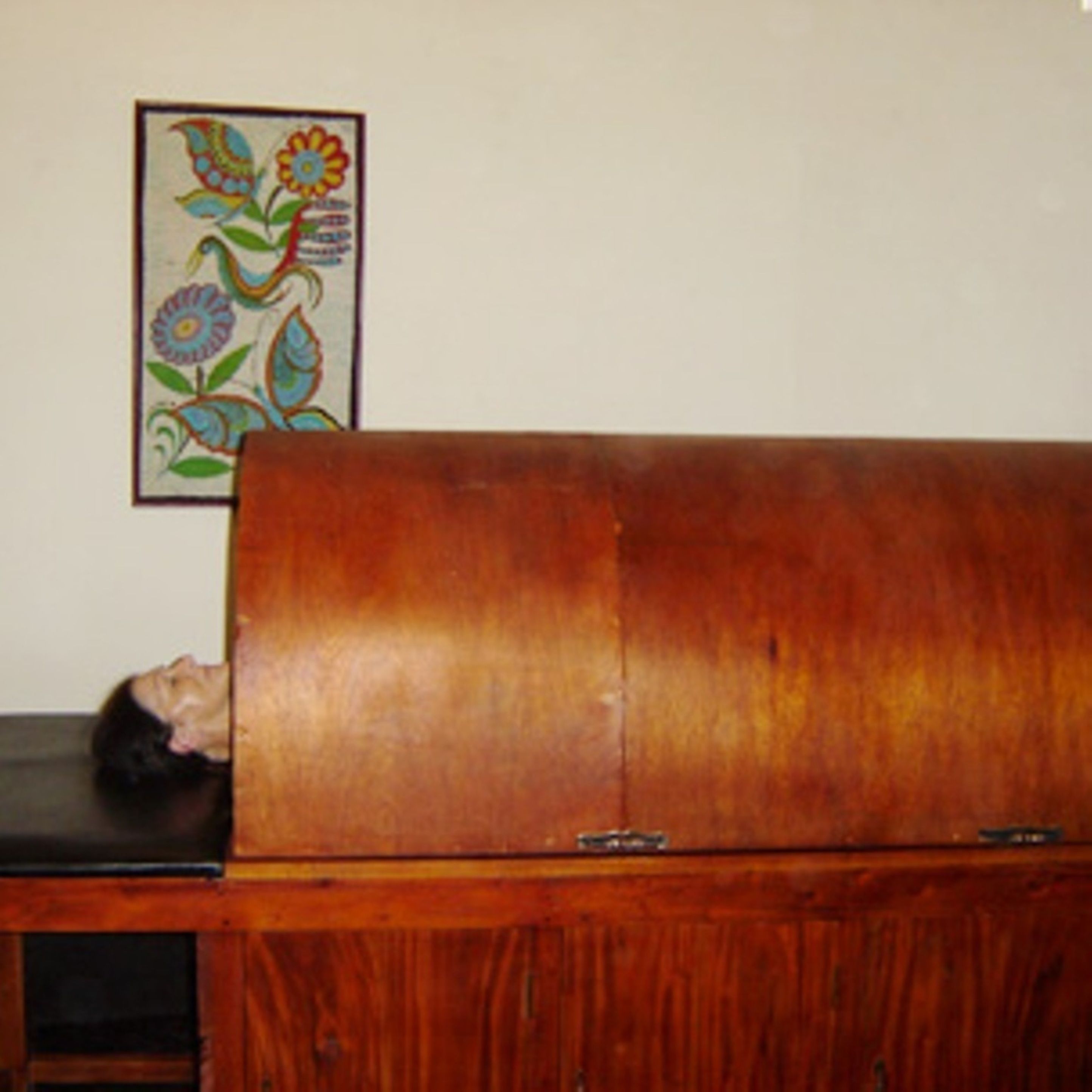 A wooden cabinet with a black object on top.