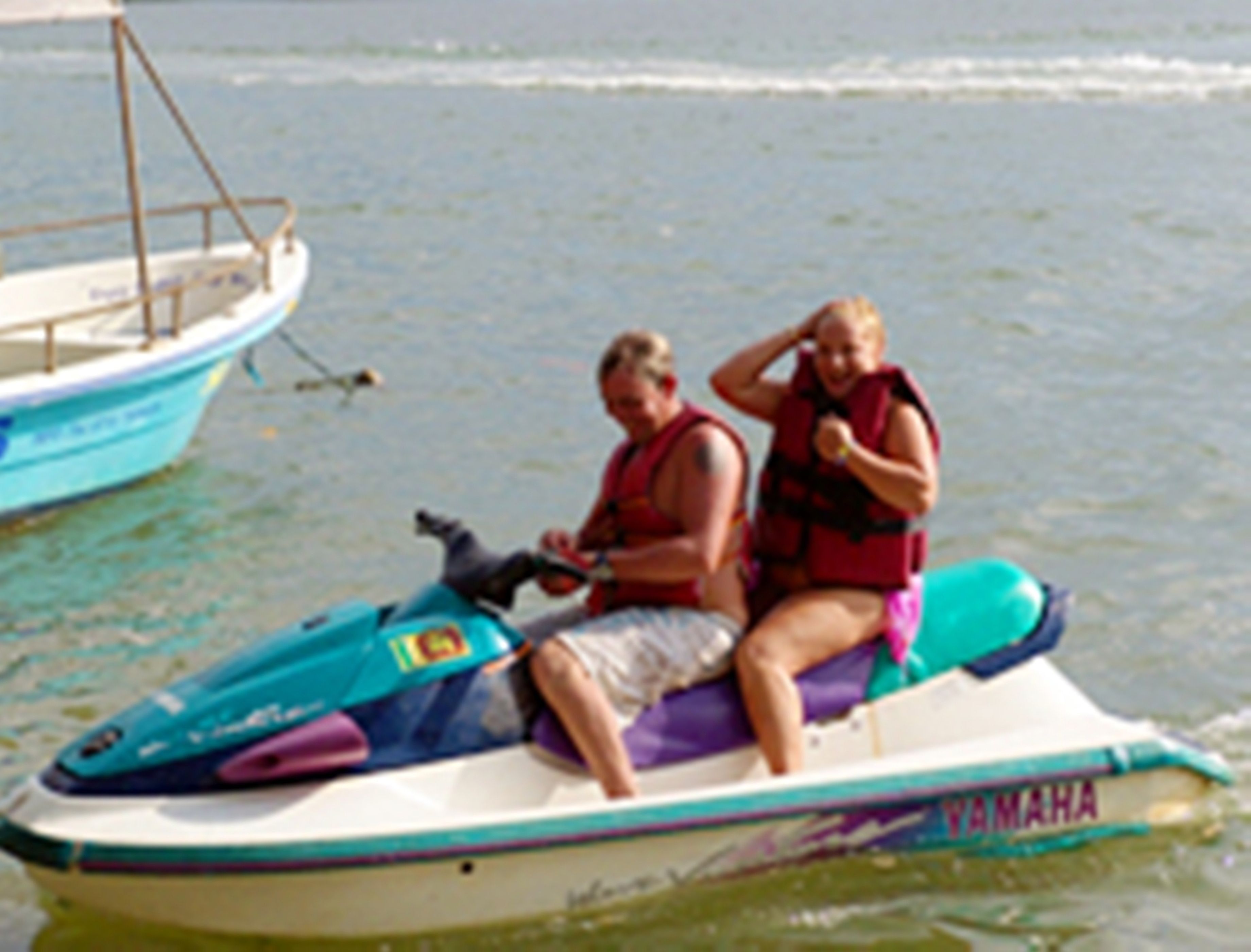 A jet ski with two people wearing life jackets on a body of water.