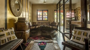A room with a large mirror, a window with a view, and a seating area with chairs and a table.