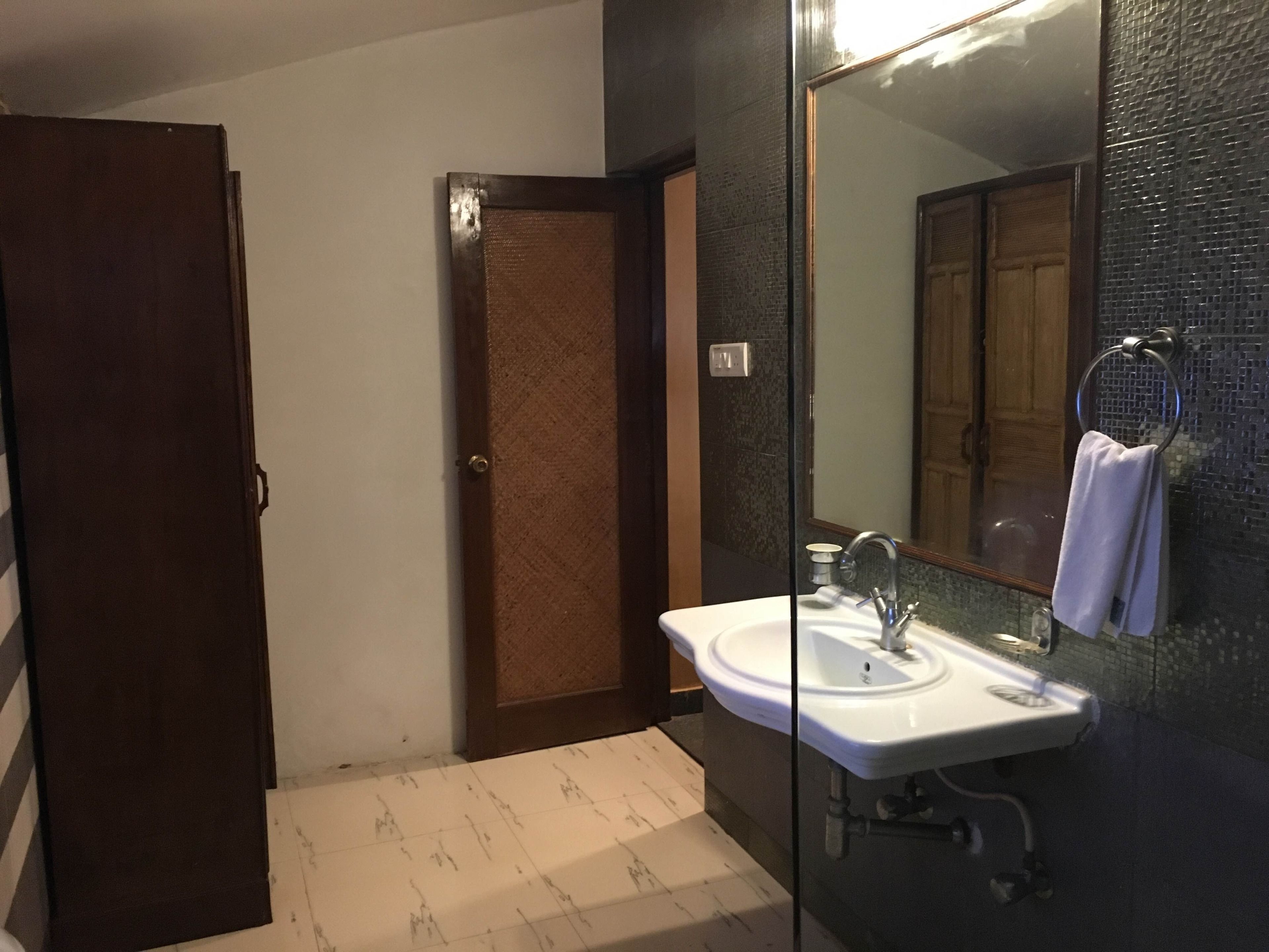 Une salle de bain avec un lavabo blanc, un miroir et une serviette suspendue à un porte-serviettes en métal.