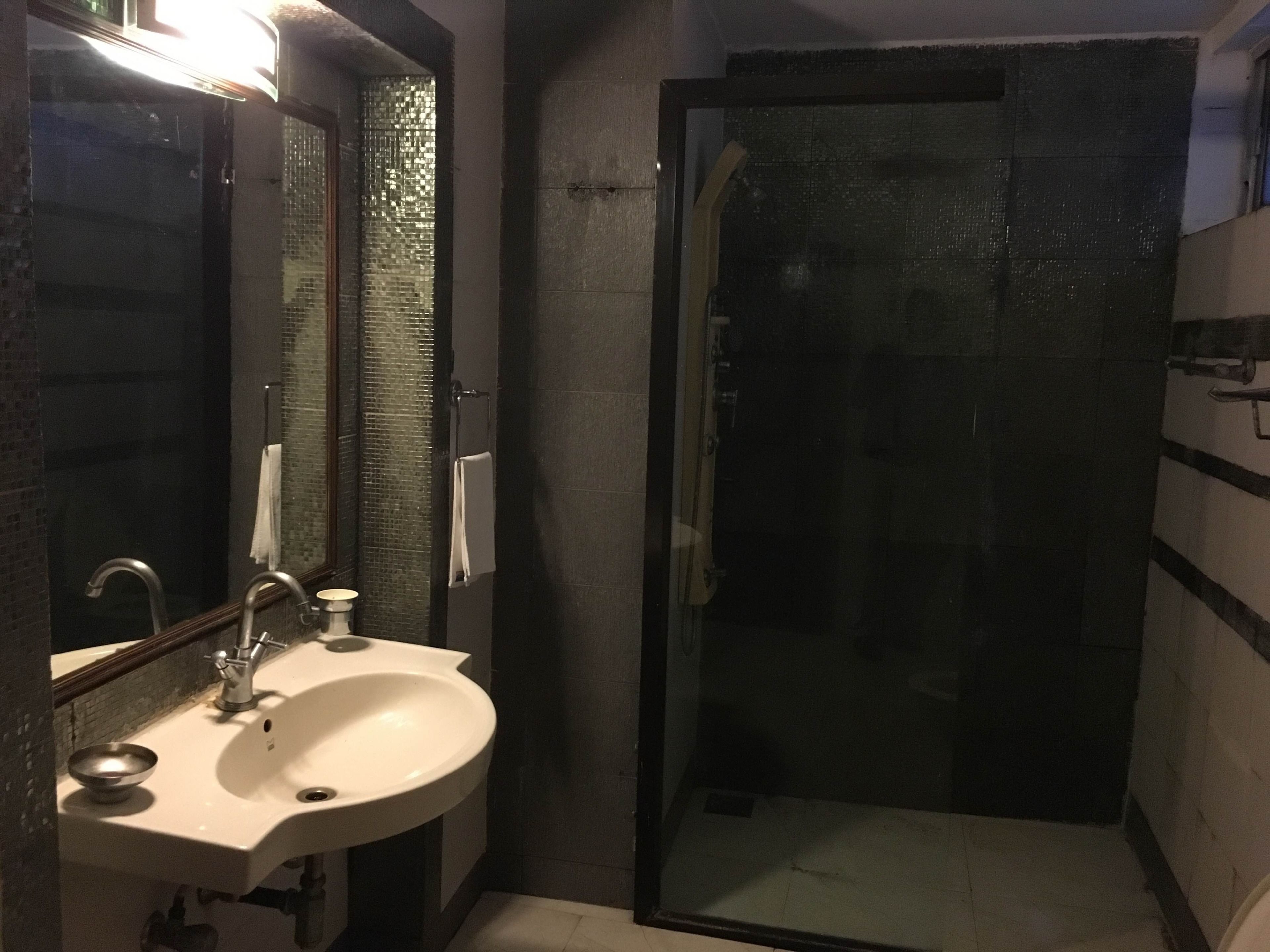 A bathroom with a sink, mirror, and shower.