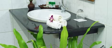 Un baño con un lavamanos blanco, un espejo y plantas verdes.