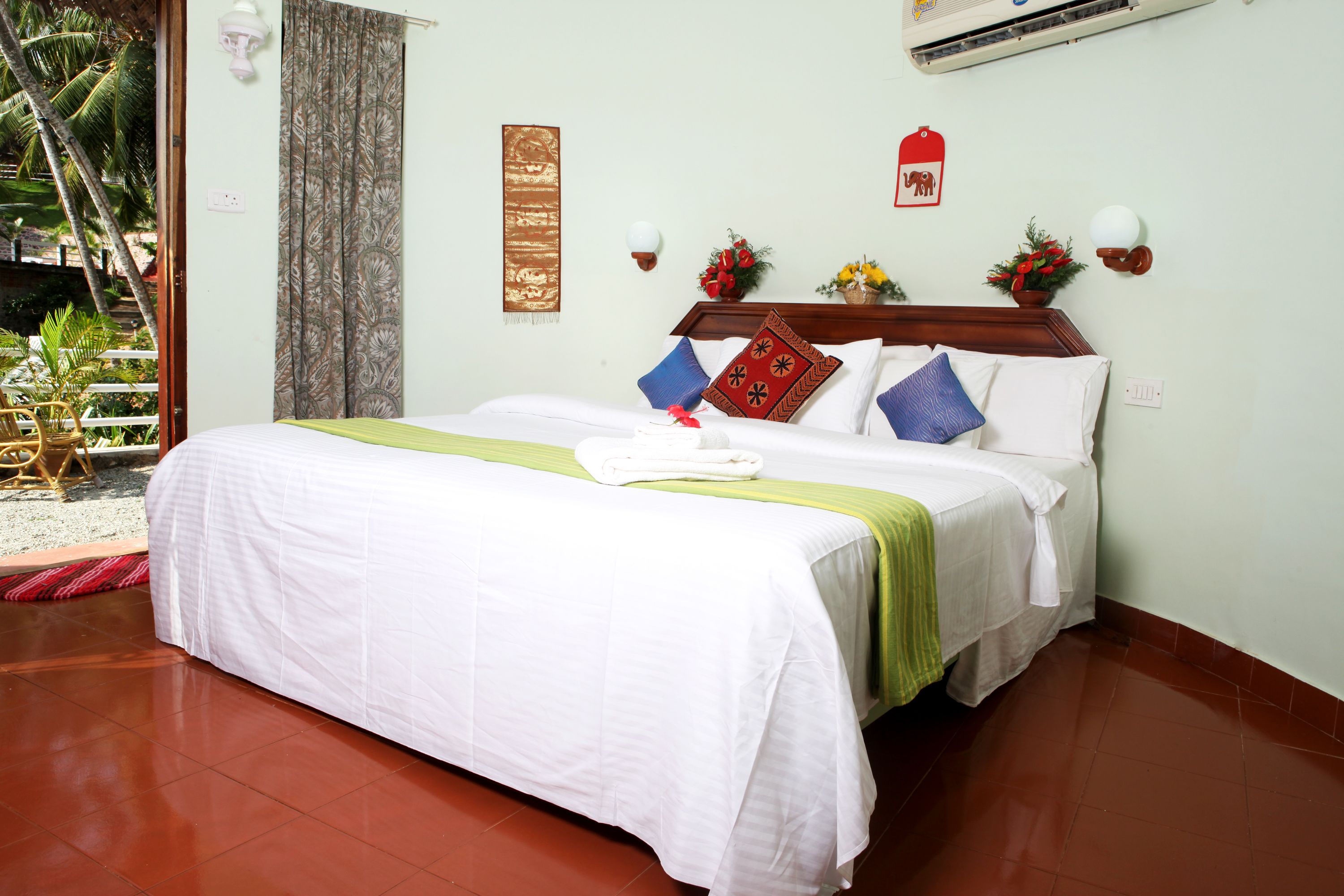 A neatly made bed with a white bedspread and green accents, a wooden headboard, and decorative pillows.