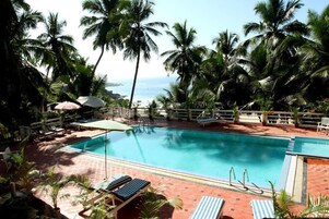 Una piscina al aire libre, sombrillas, tumbonas
