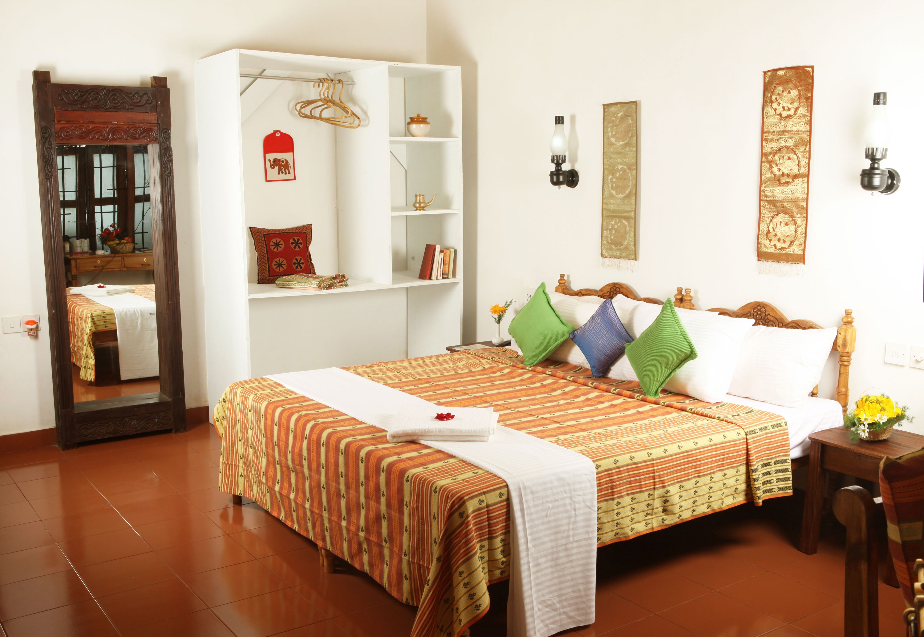 Habitación de hotel con una cama grande, un armario, un espejo y una pared decorada.