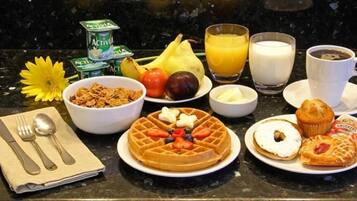 Una mesa de desayuno con waffles, muffins y fruta sobre una encimera de cocina.