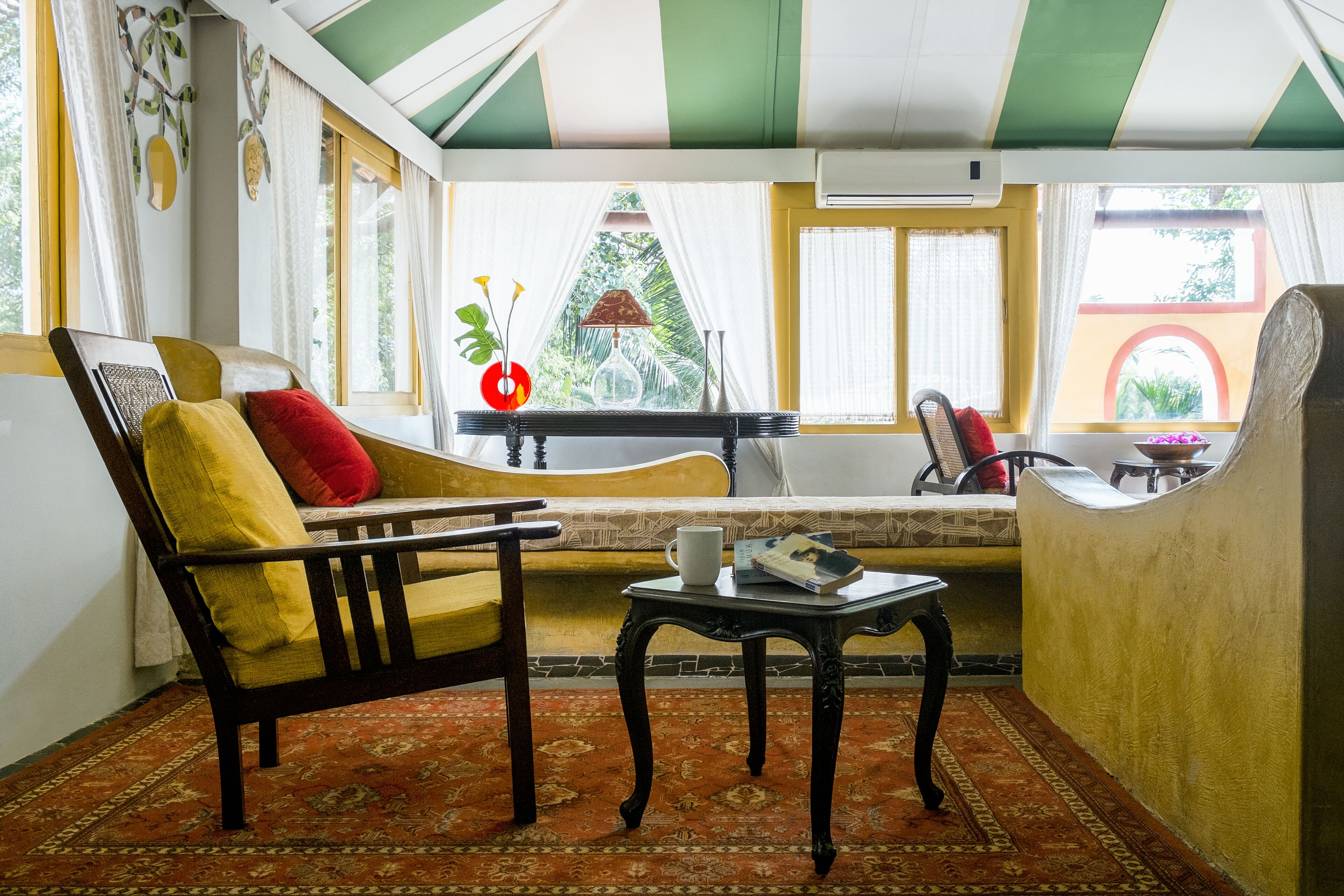 Une pièce avec un canapé, une petite table et une fenêtre avec des rideaux.