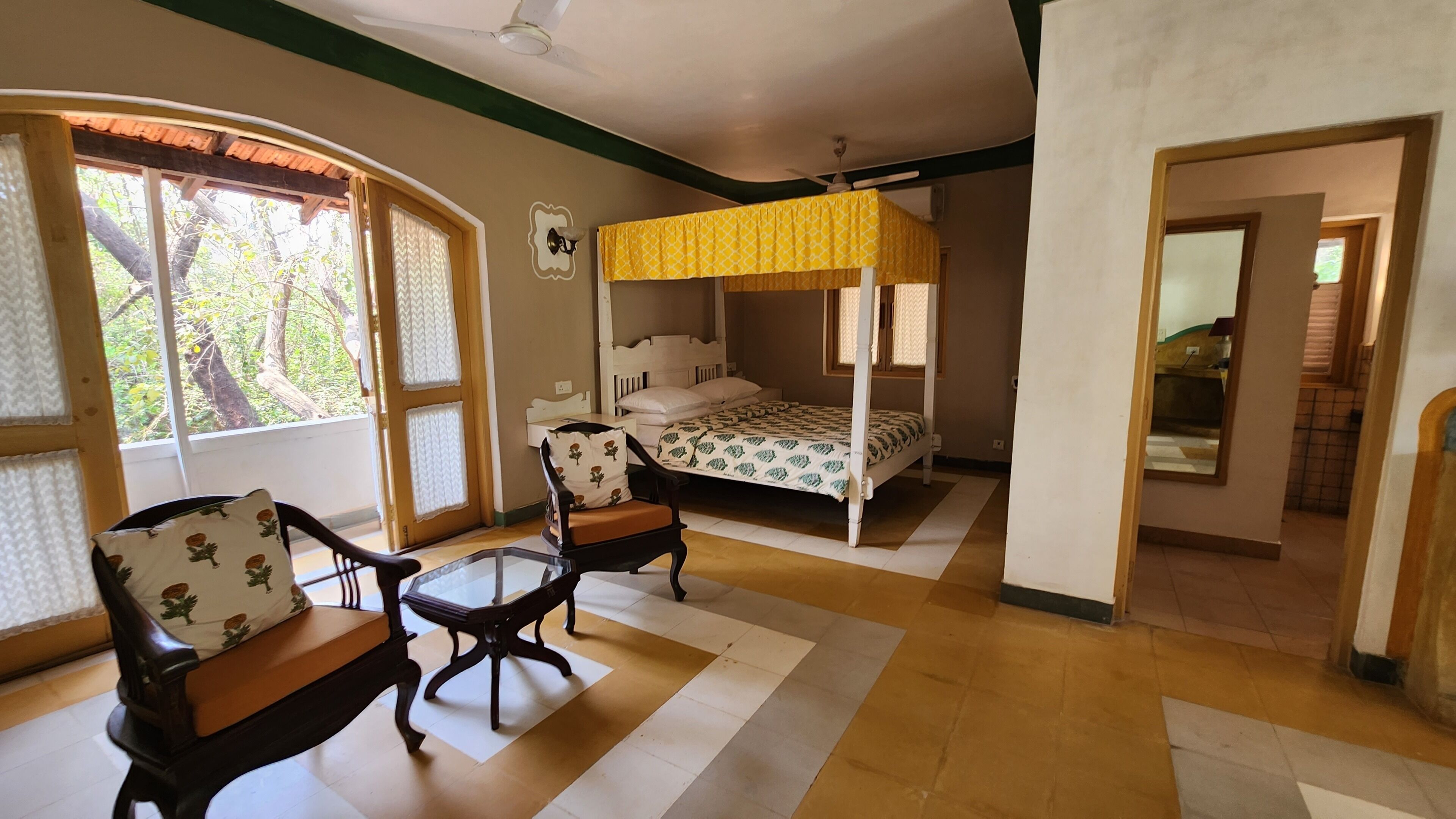A room with a bed, a chair, a table, and a window with curtains.