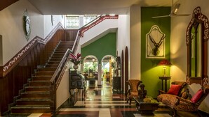 A grand lobby with a wooden staircase, a green wall, and traditional furnishings. - Casa Anjuna (Anjuna)