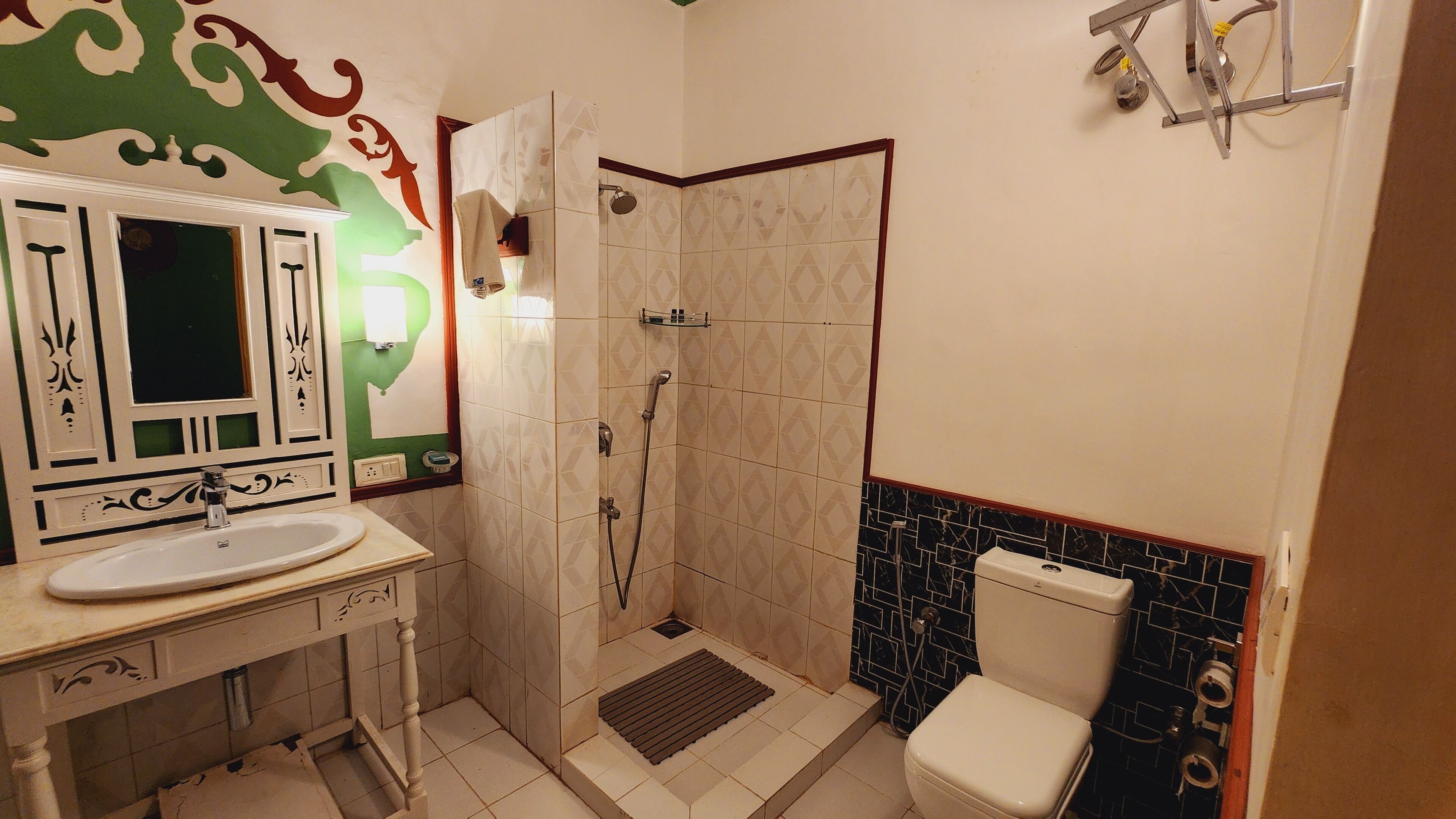 A bathroom with a sink, mirror, shower, and toilet.