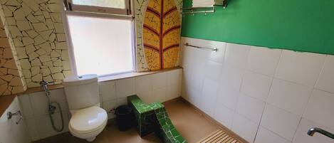 A bathroom with a toilet, a green sink, a window, and a towel rack.