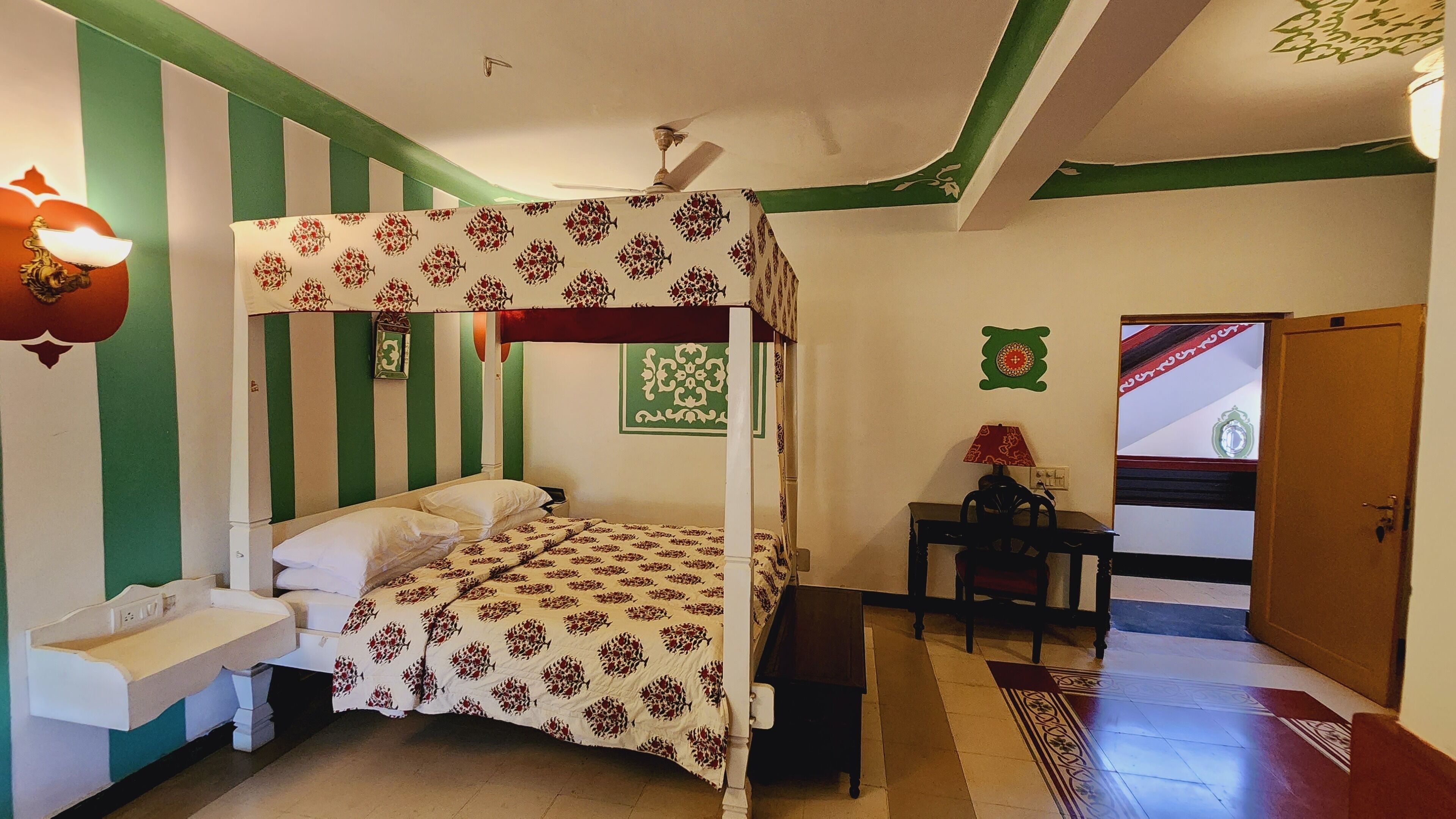 Un lit superposé avec une couvre-lit à motifs, une table de chevet avec une lampe et une petite chaise.