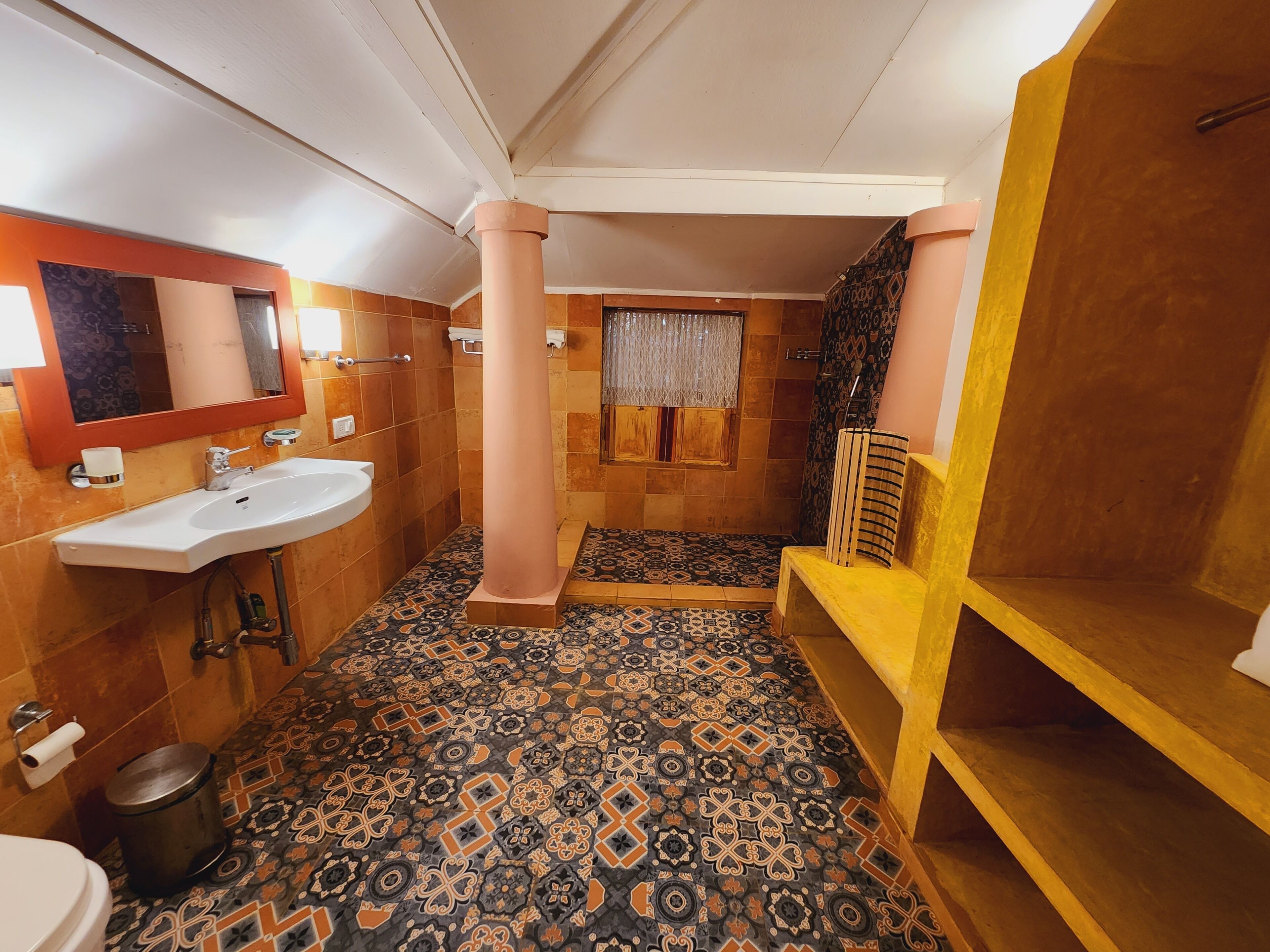 A bathroom with a sink, mirror, toilet, and shower area.