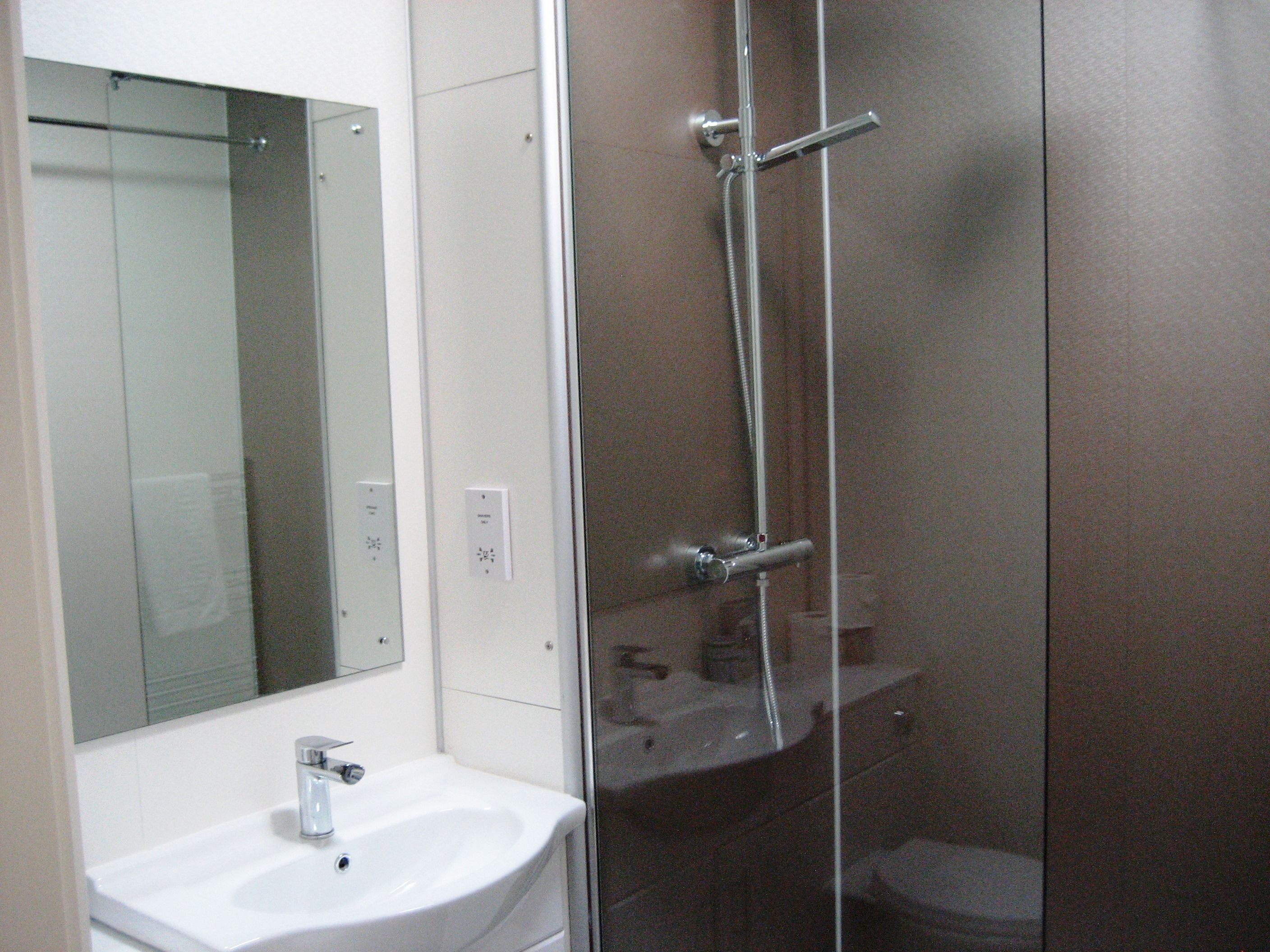 Un bagno con un lavandino bianco, uno specchio e una cabina doccia in vetro.