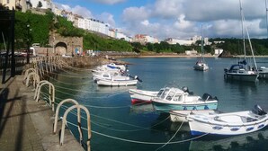 A harbor with boats docked, a stone bridge, and buildings in the background. - Glenholme Apartments (Tenby)