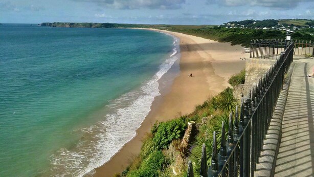 A coastal beach with a paved walkway and a stone wall. - Glenholme Apartments (Tenby)
