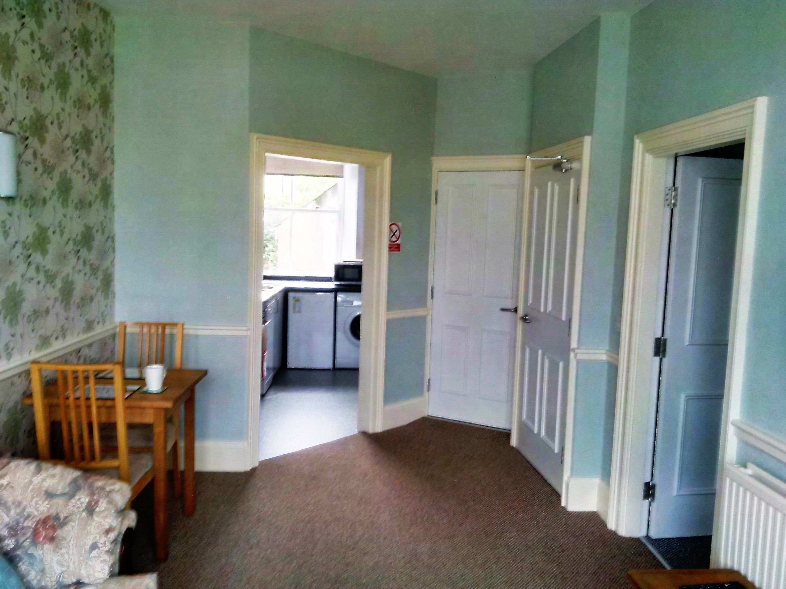 Un pasillo con comedor, lavadora y puerta que da a otra habitación.