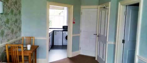 Un pasillo con comedor, lavadora y puerta que da a otra habitación.