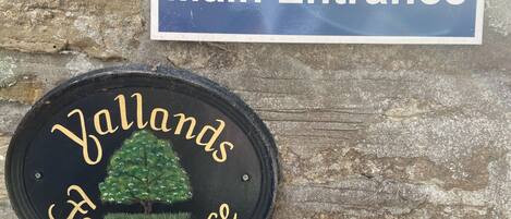 Un cartel que indica 'Main Entrance' y un cartel circular que dice 'Yallands Farmhouse'.