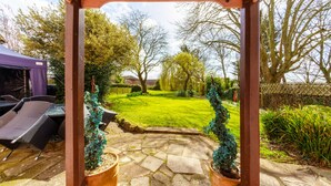 A patio area with stone flooring, two potted plants, and a purple tent in the background. - Yallands Farmhouse (Taunton)