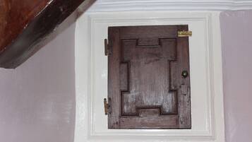 A wooden door with a brass handle and a brass doorknob, set in a white wall with a decorative molding.
