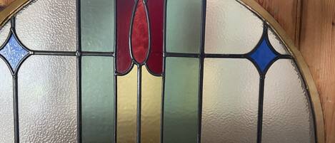 A stained glass window with a semi-circular top and a grid of colored glass panes.