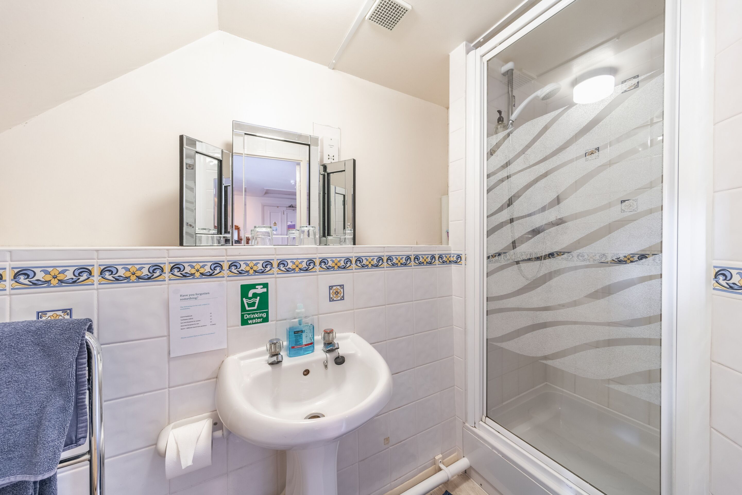 A bathroom with a white sink, a mirror, and a shower with a glass door.