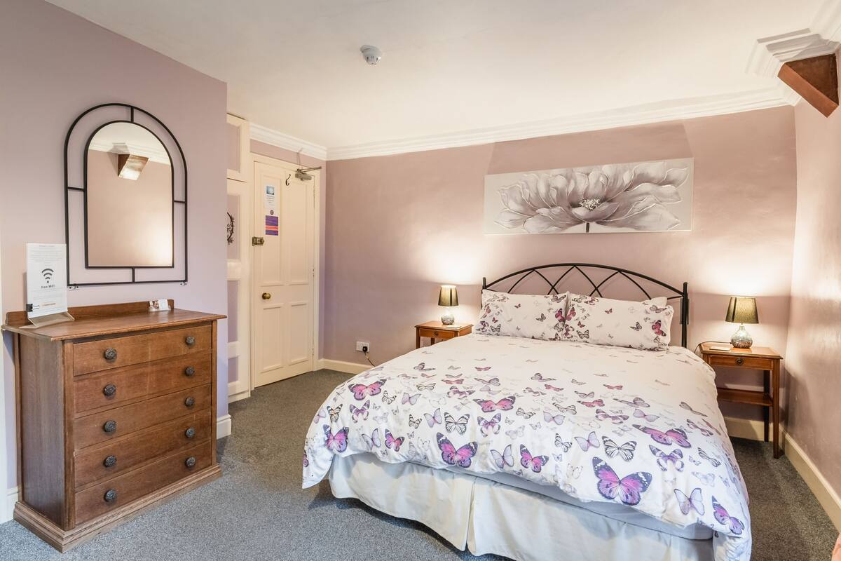 Ein Schlafzimmer mit Bett, Kommode und Spiegel.