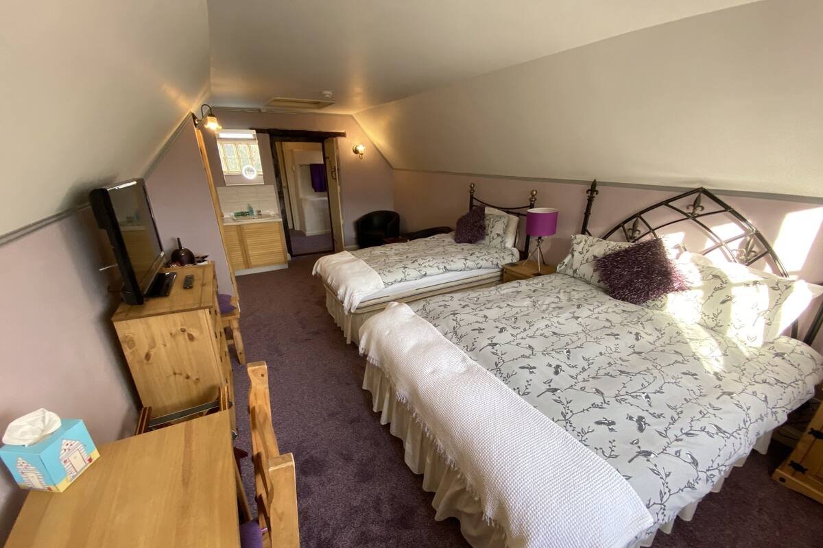 Ein Schlafzimmer mit zwei Betten, einem Holztisch, einem Spiegel und einem Fenster.