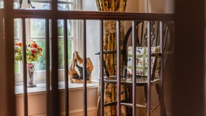 A window with a view of a garden, a chair with floral upholstery, and a decorative item on the windowsill. - Yallands Farmhouse (Taunton)