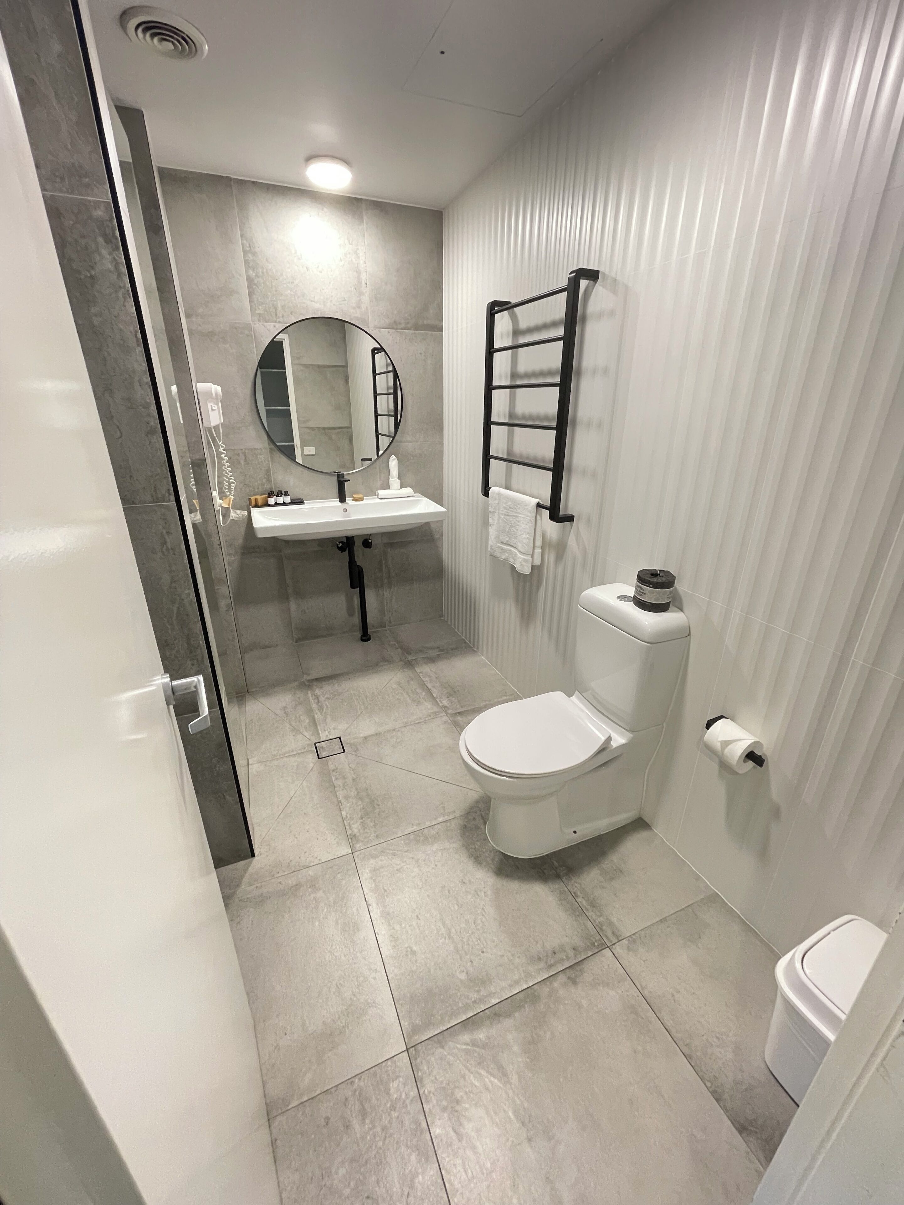 A modern bathroom with a toilet, sink, and mirror.