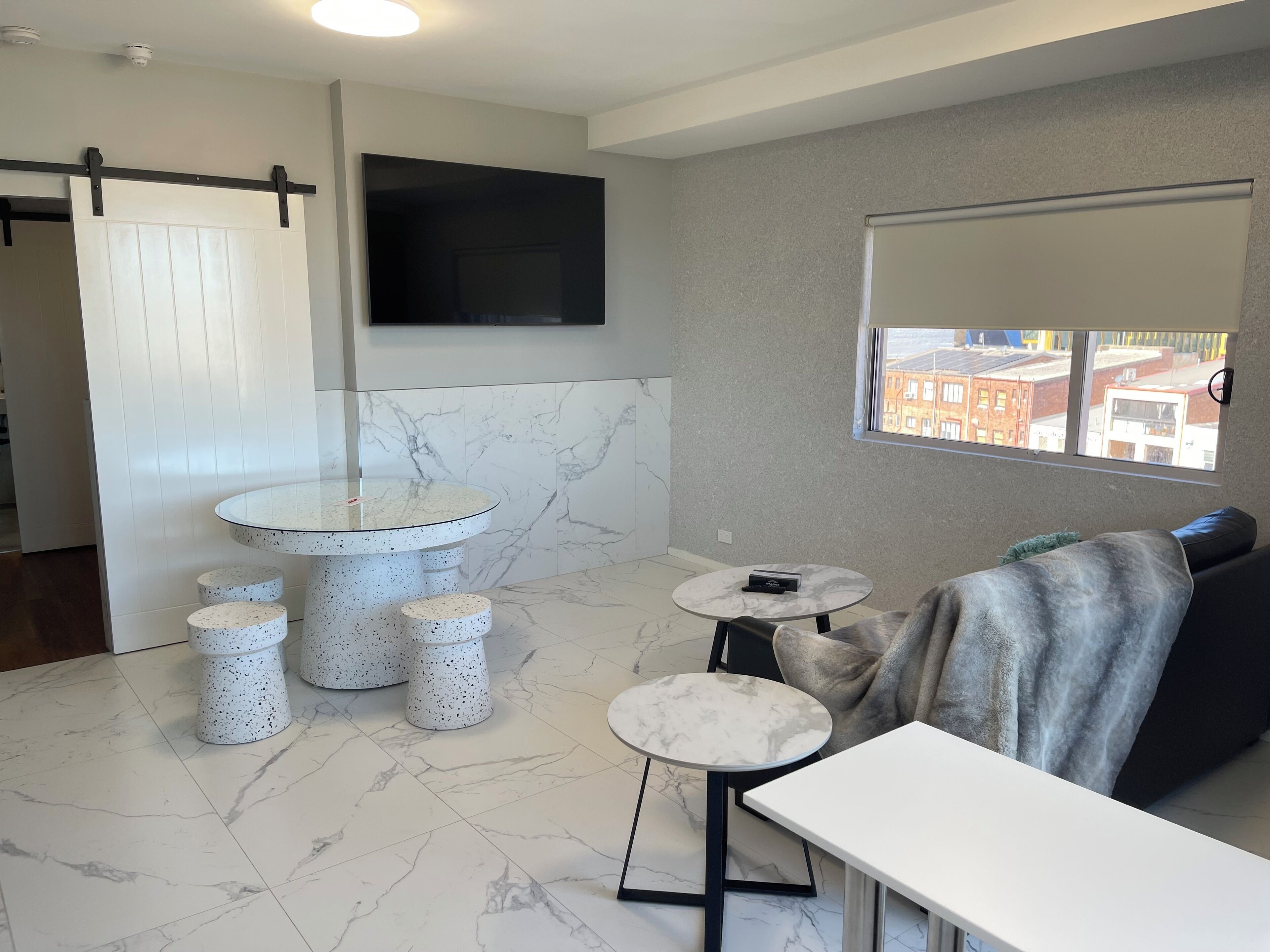 Uma casa de banho moderna com soalho em mármore, uma sanita, um lavatório redondo e uma pequena mesa.