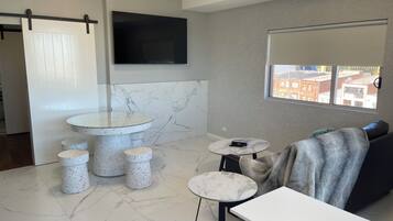 Uma casa de banho moderna com soalho em mármore, uma sanita, um lavatório redondo e uma pequena mesa.