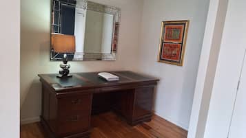 A wooden desk with drawers, a mirror, and a lamp.