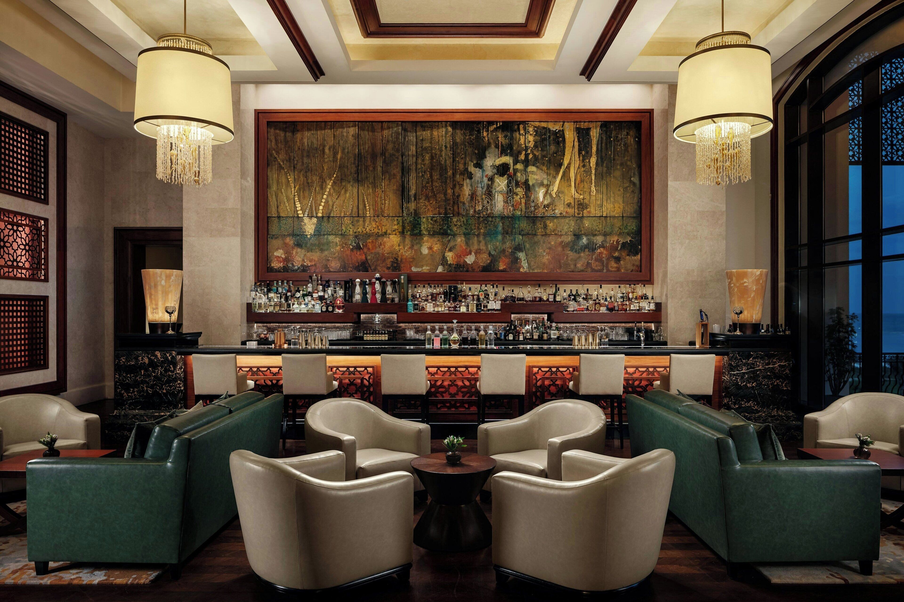 A bar area with leather sofas, a large mural, and a well-stocked bar.