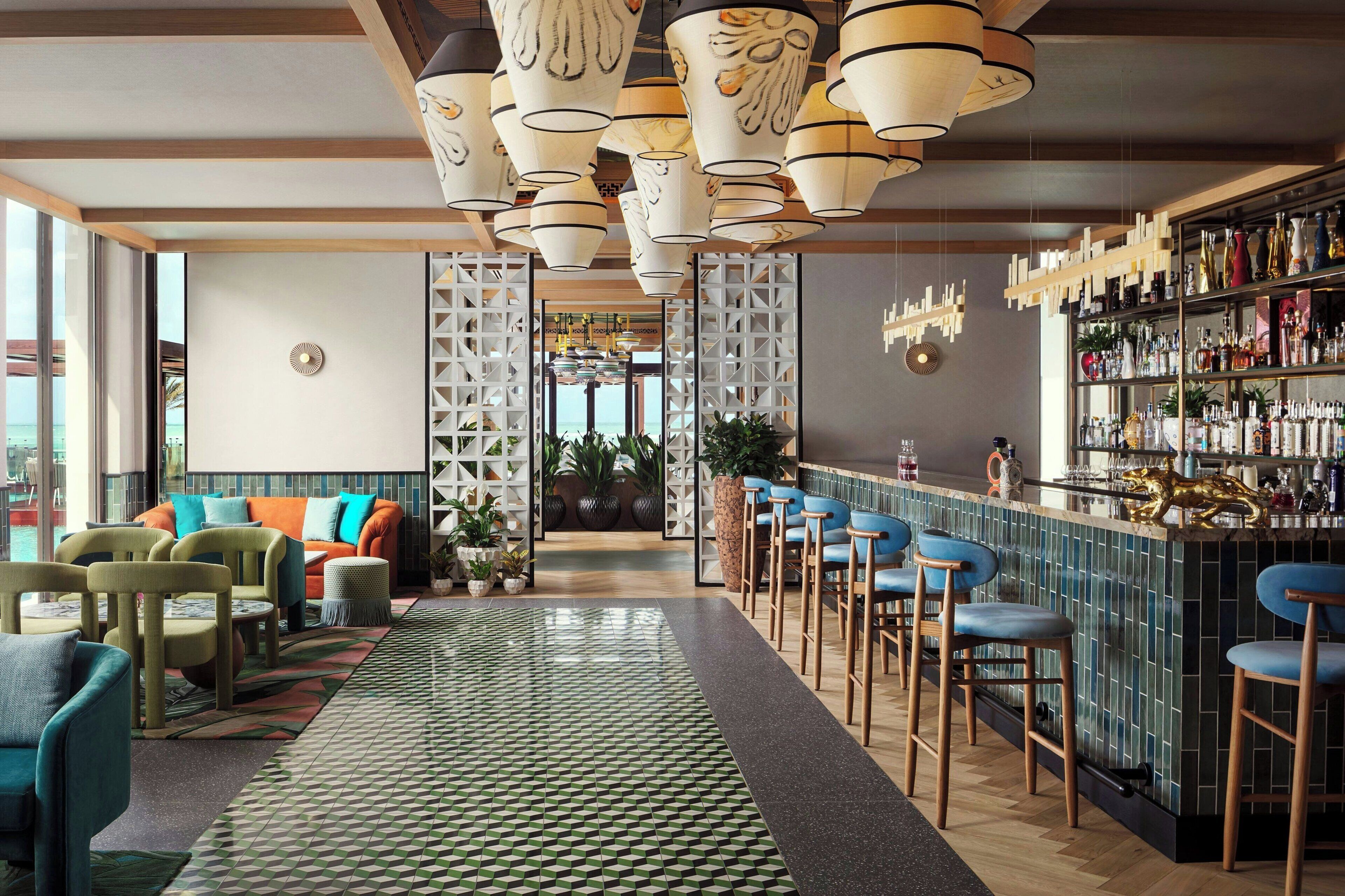 A modern bar area with a patterned floor, seating, and a bar stocked with bottles.
