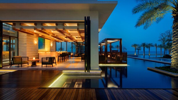 Un resort moderno con piscina, terraza de madera y zona de estar al aire libre.