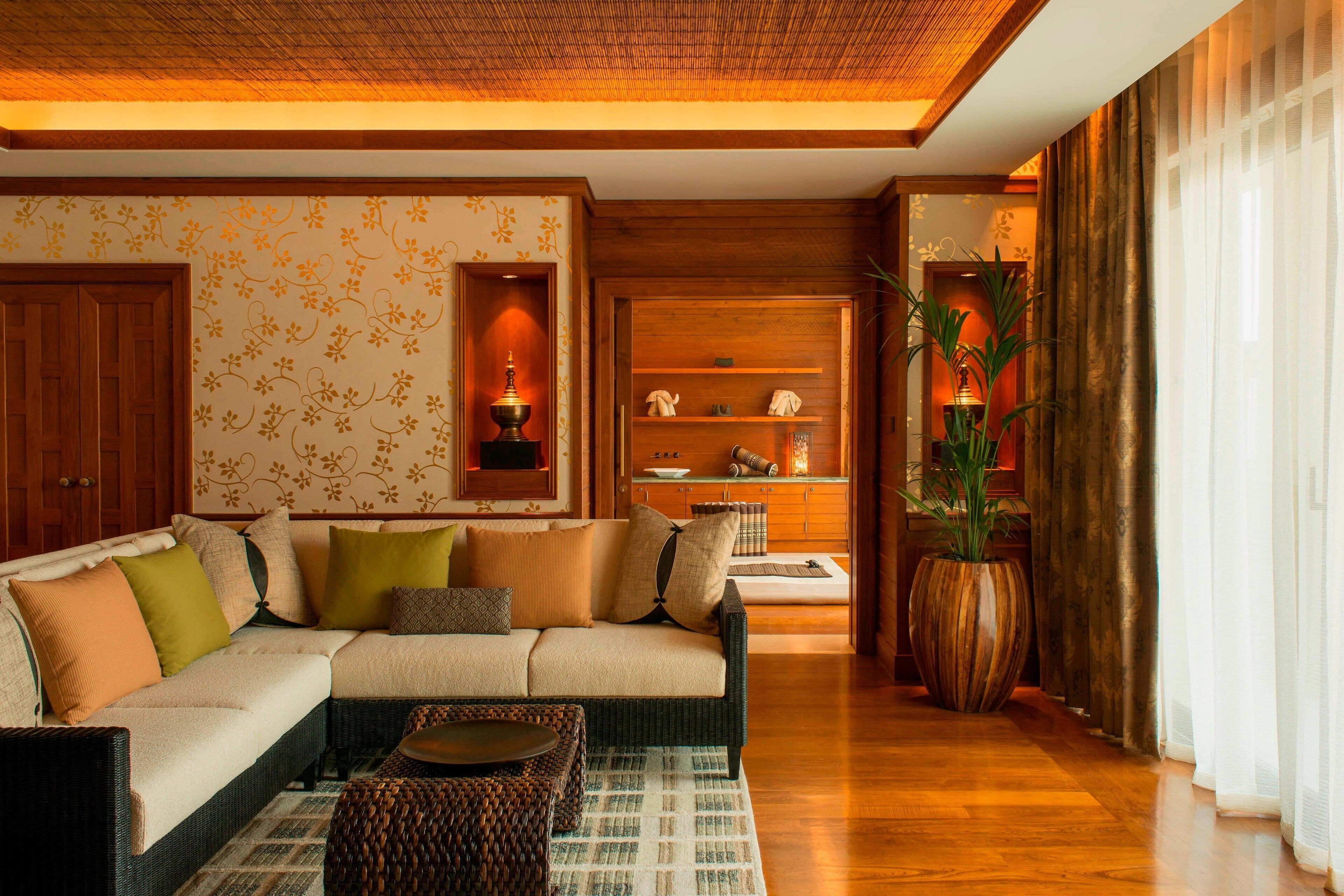 A cozy living room with a sectional sofa, a coffee table, and a large potted plant.