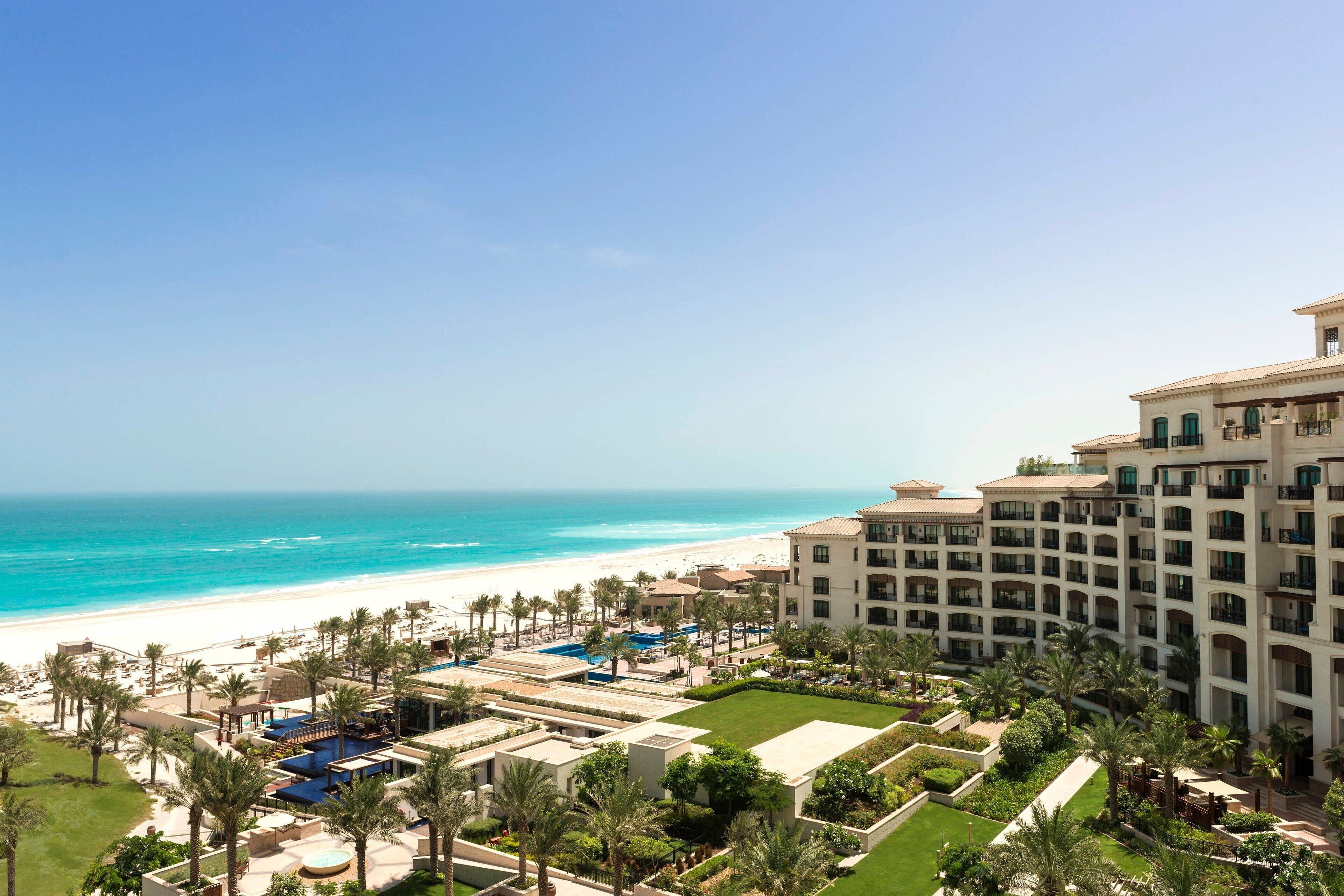 A resort with a beach view, multiple swimming pools, and lush landscaping.