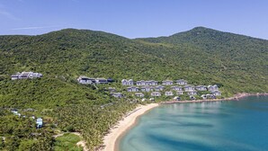 Un resort con diversi edifici su una collina che si affaccia su una spiaggia e sul mare.