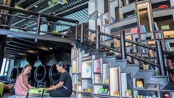 Staircase leads to an upper level, flanked by bookshelves and seating areas.