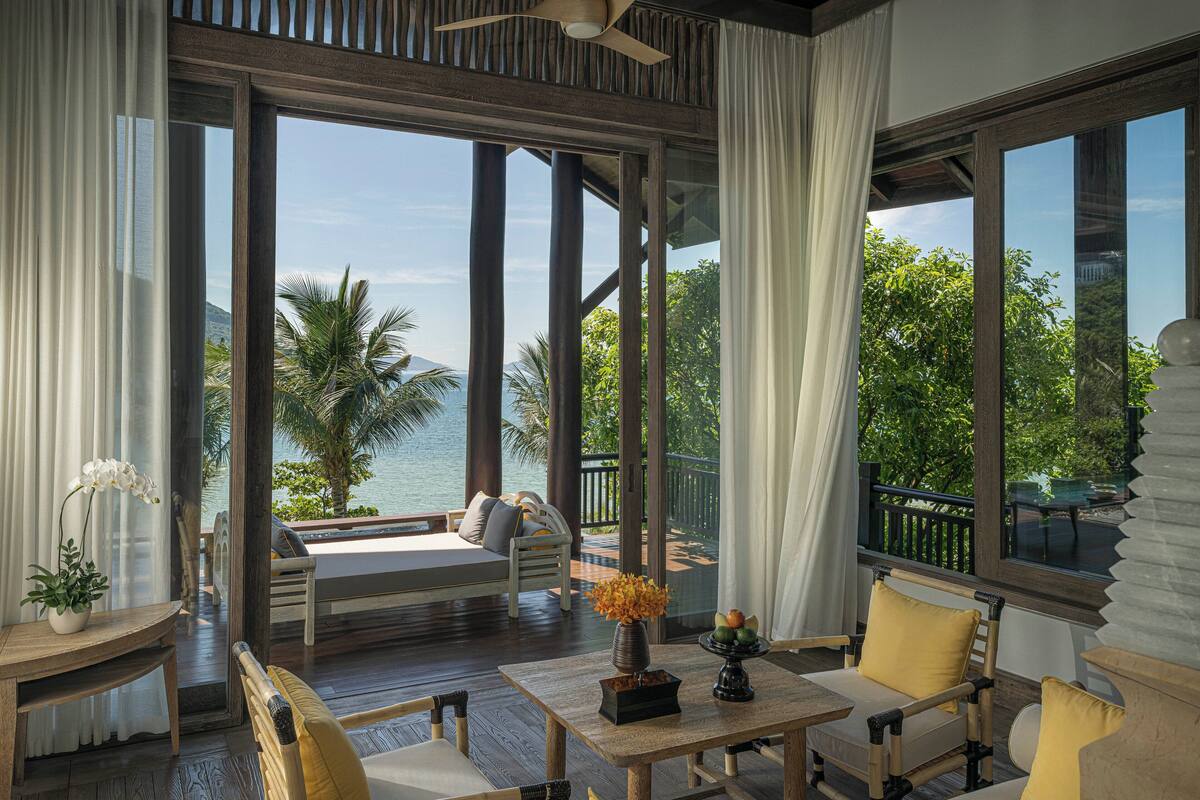 A spacious balcony with a wooden deck, a seating area with cushions, and a view of the ocean.