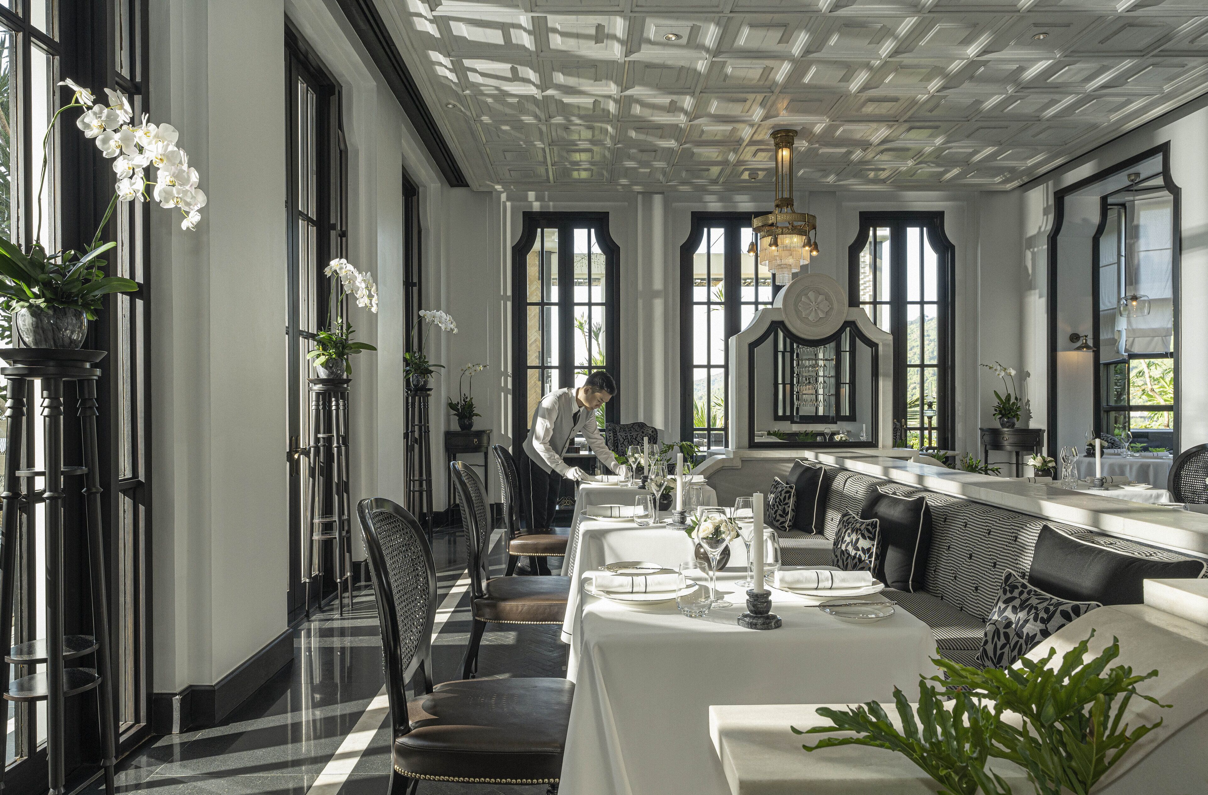 A formal dining area with a long table, black and white checkered floor, and large windows.