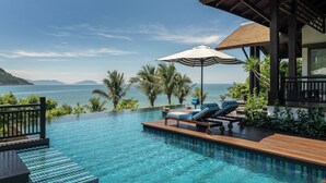 A poolside area with lounge chairs and a view of the sea.