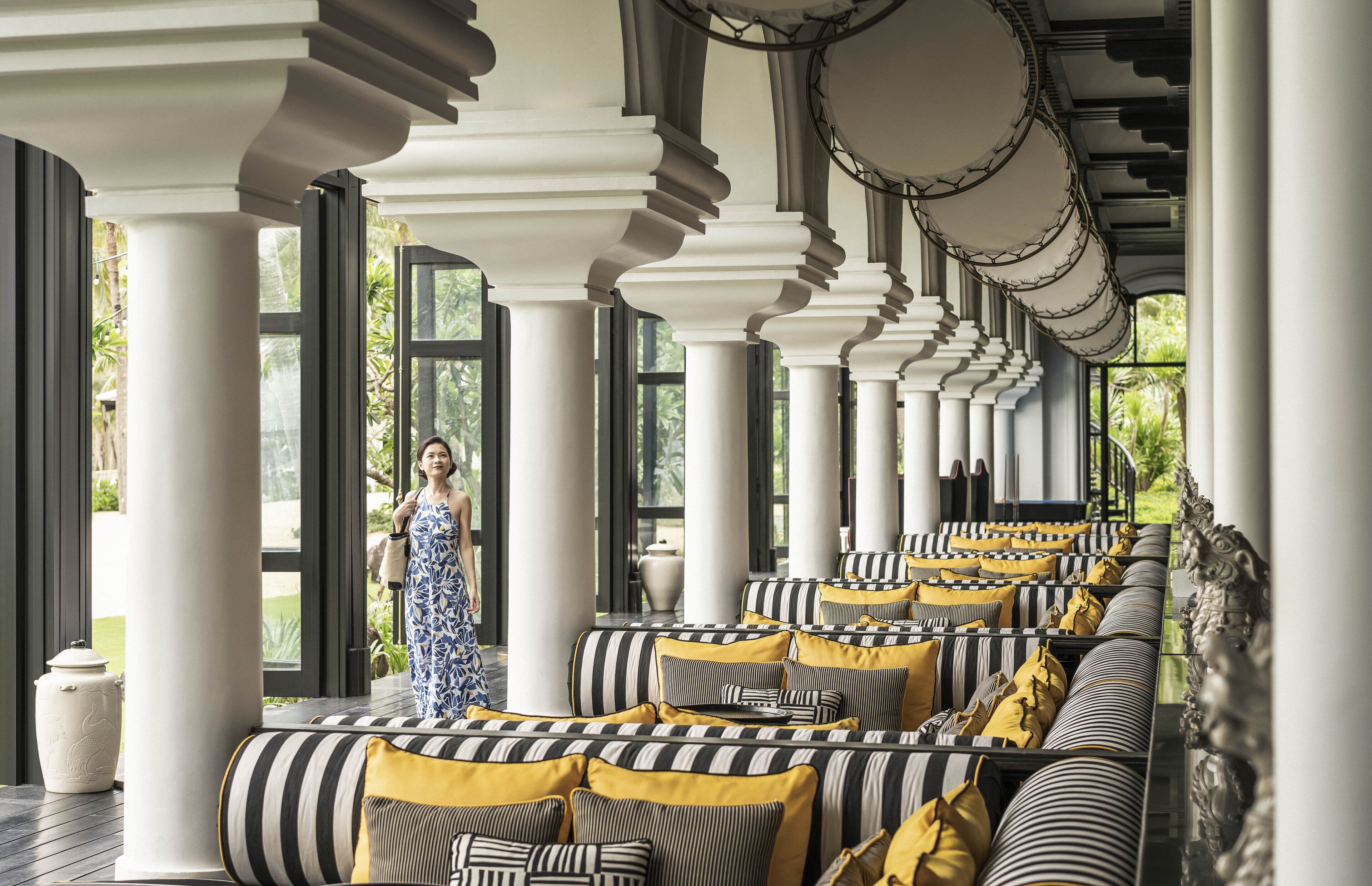 A covered outdoor seating area with striped cushions and columns.