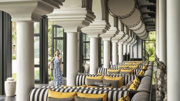 A covered outdoor seating area with striped cushions and columns.