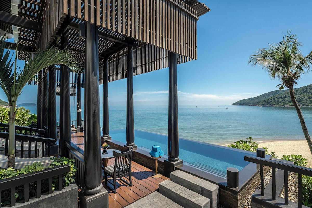 A resort with a pool, outdoor seating, and a view of the sea.